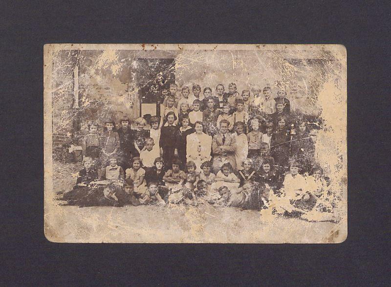 Uczniowie wraz z nauczycielem na tle budynku szkoły w Gnieźnie.