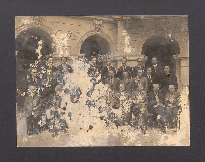 Grupa mężczyzn na dziedzińcu budynku.