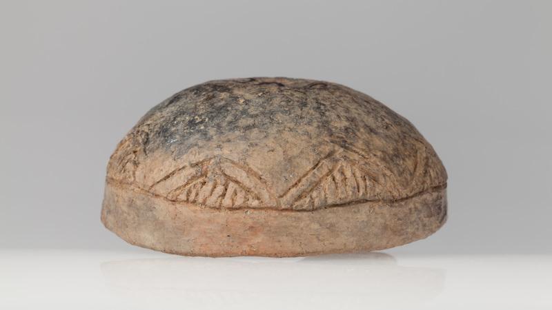 Czerpak półkulisty z wklęsłym dnem, zdobiony dookolnym rytym rowkiem i zwężającymi się trójkątami