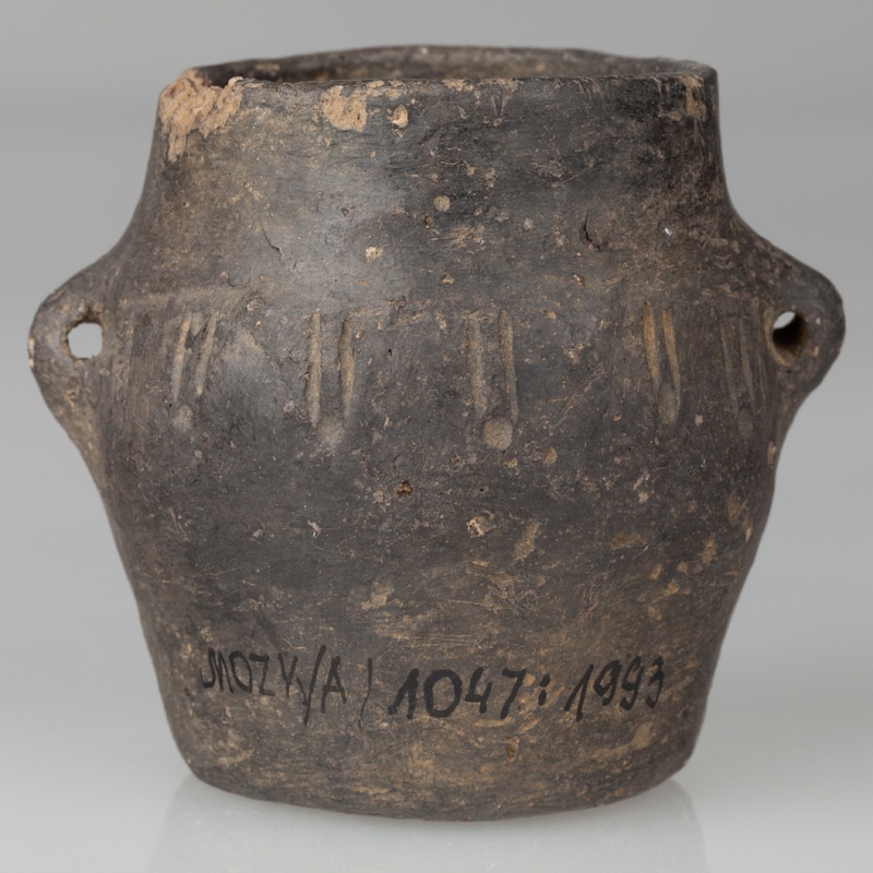 Garnek beczułkowaty, zaopatrzony w dwa kolankowate uszka