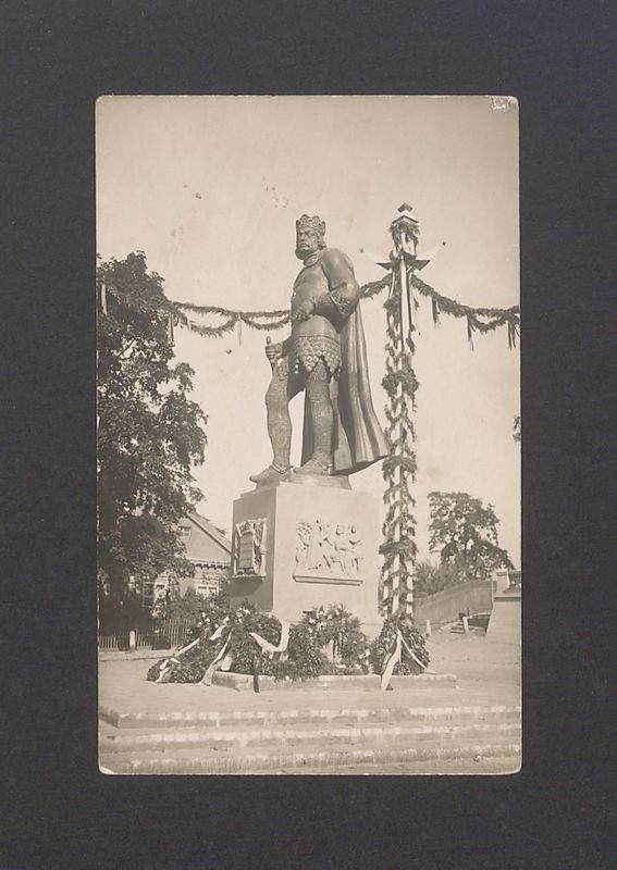 Pomnik Bolesława Chrobrego otoczony wieńcami z kwiatów i rozwieszonymi wokoło girlandami.