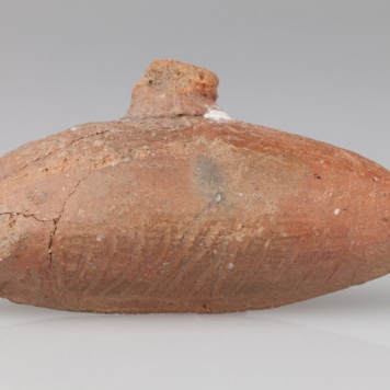 Grzechotka ornitomorficzna zdobiona ornamentem rytym.