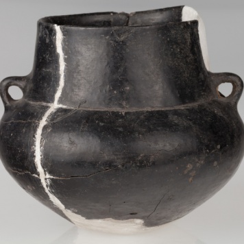 Amfora o baniastym brzuścu, stożkowatej szyjce, zaopatrzona w dwa ucha. Naczynie zdobione dookolnym rowkiem