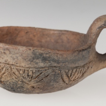 Czerpak półkulisty z wklęsłym dnem, zdobiony dookolnym rytym rowkiem i zwężającymi się trójkątami