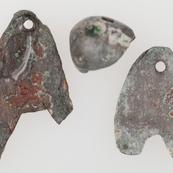 Dwie sercowate zawieszki wykonane z cienkiej blachy brązowej, zaopatrzone w dwa otwory